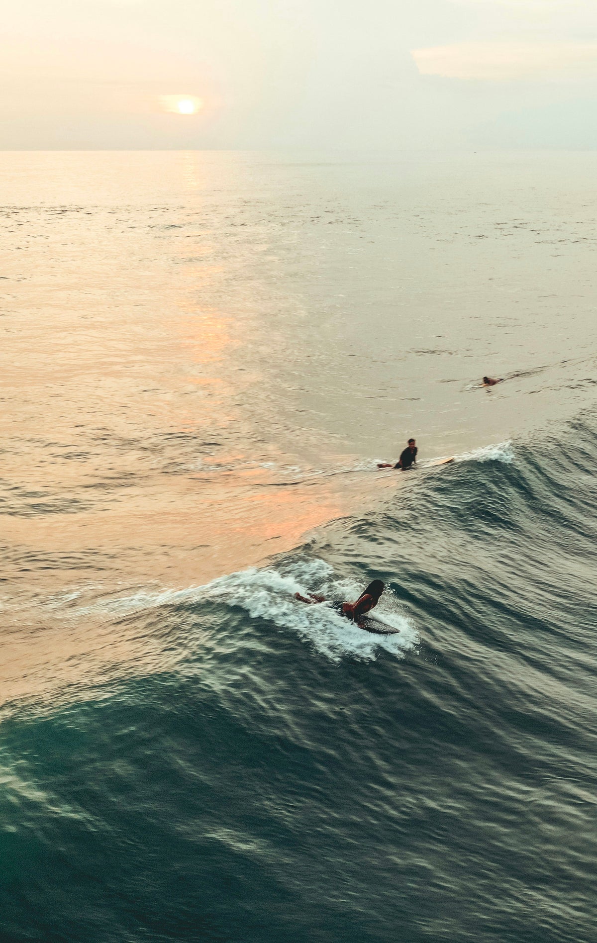 Surfers in the water at golden hour in Canggu, Bali