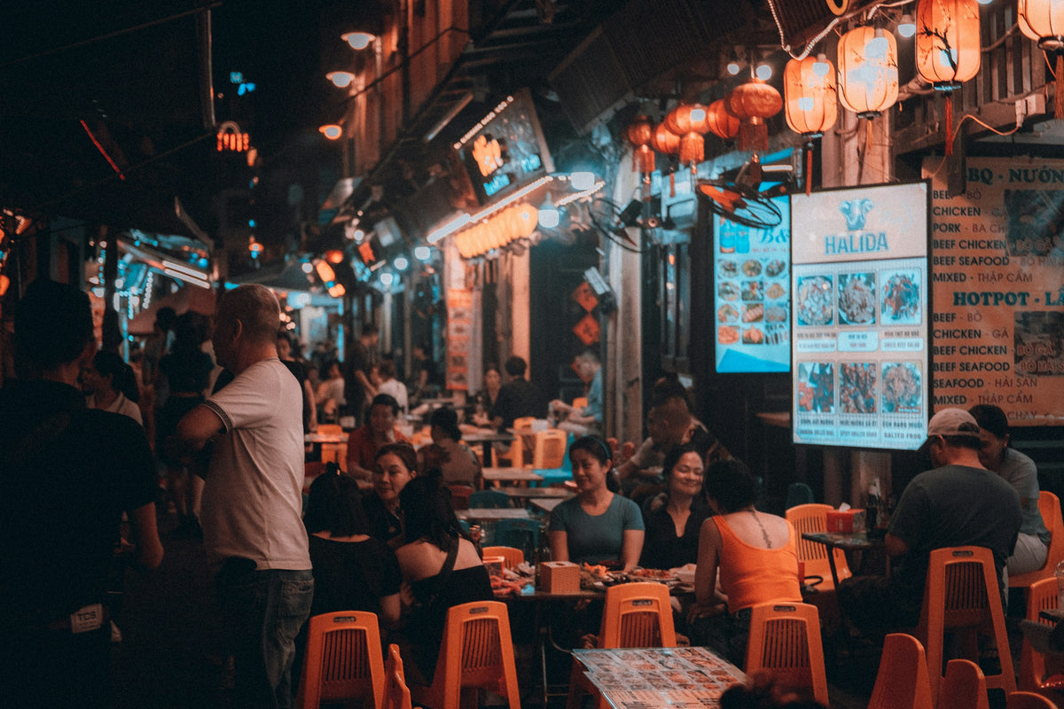 People eating street food at a busy night market in Hanoi, Vietnam